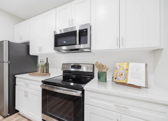 a white kitchen with stainless steel appliances and a microwave at The Lena, Raritan, NJ 08869