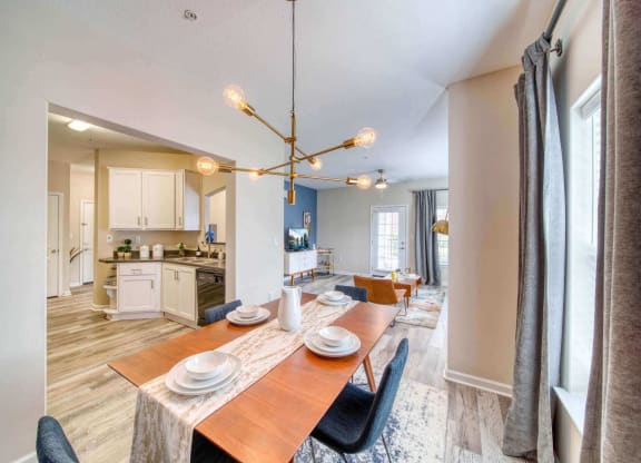 a dining area with a wooden table and chairs and a kitchen in the background at Meridian Obici, Suffolk, VA