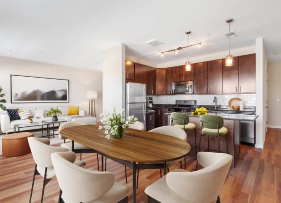 a living and dining room area with a kitchen in the background and a large table in the at West 130, West Hempstead New York