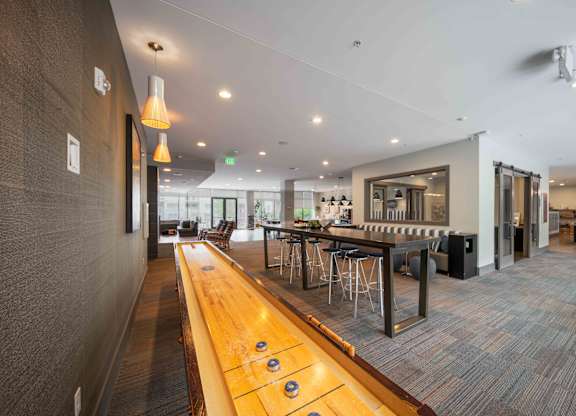 A long wooden table with several stools is in the middle of a room at Regatta Sloans Lake Apartments, Colorado