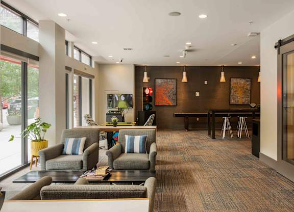 A modern waiting room with grey couches and a wooden floor at Regatta Sloans Lake Apartments, Denver 80204