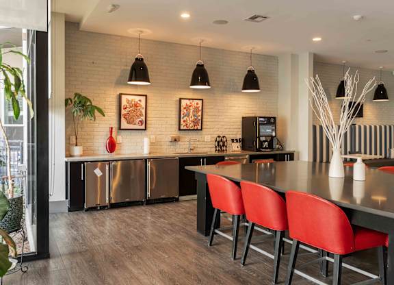 A modern kitchen with red chairs and a wooden floor at Regatta Sloans Lake Apartments, Denver, Colorado