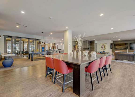 A modern kitchen with a long island and red chairs at Regatta Sloans Lake Apartments, Colorado, 80204