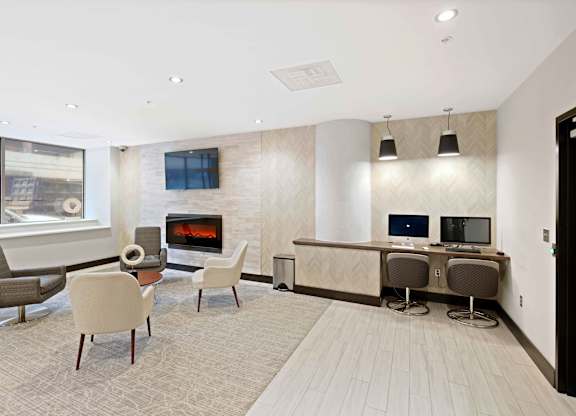 A modern living room with a fireplace and a desk with two computers.