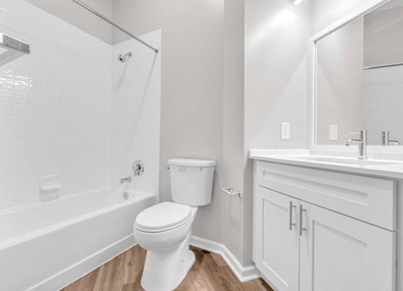 A white toilet in a bathroom with a white tub and sink.