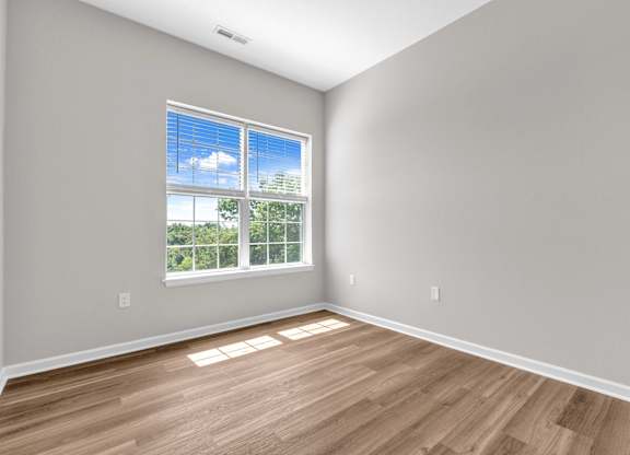 A room with a large window and wooden flooring.