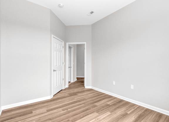 A room with wooden flooring and two doors.