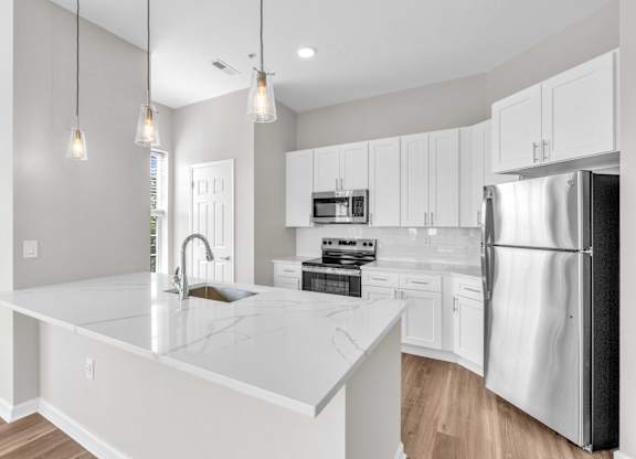 A modern kitchen with a white countertop and stainless steel appliances.