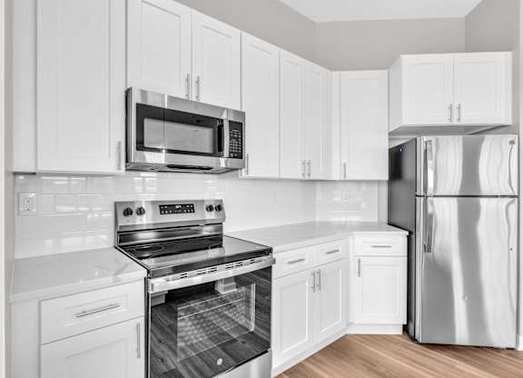 A modern kitchen with white cabinets and stainless steel appliances.