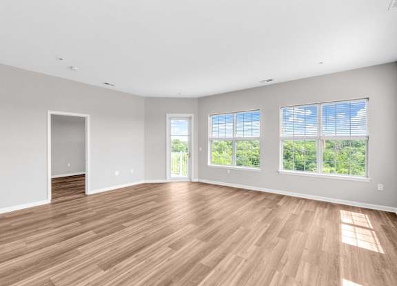A large empty room with wooden floors and windows.