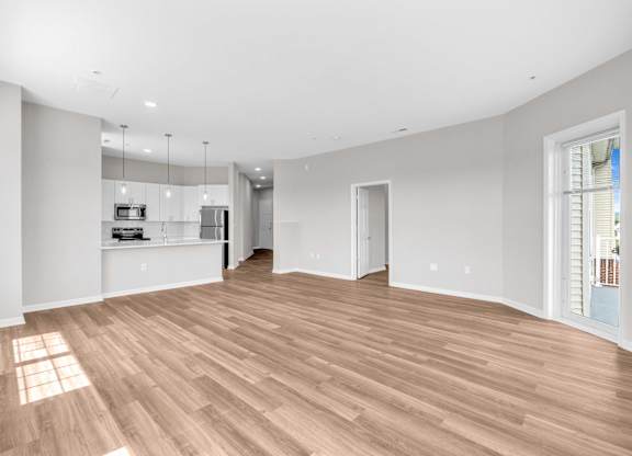 A spacious room with wooden flooring and white walls.