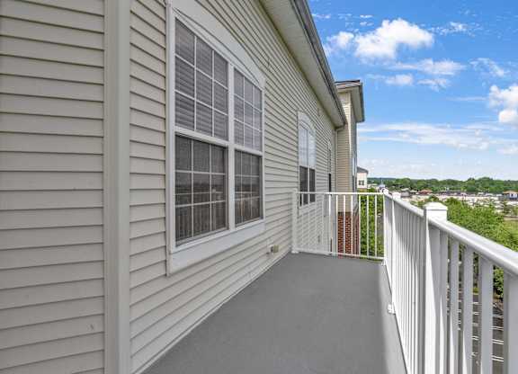 A balcony with a white railing and a sliding glass door.