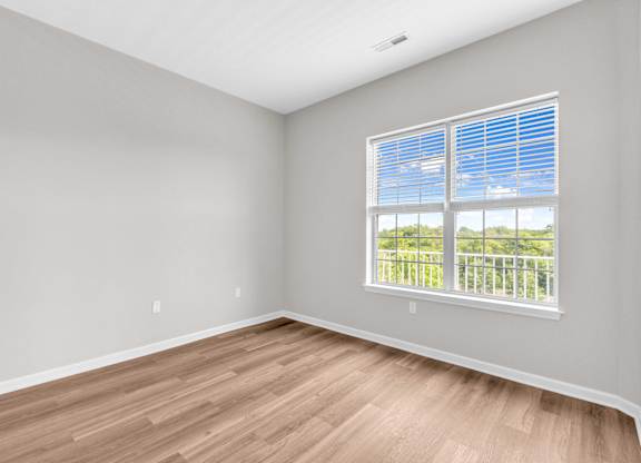 A room with a window and wooden flooring.