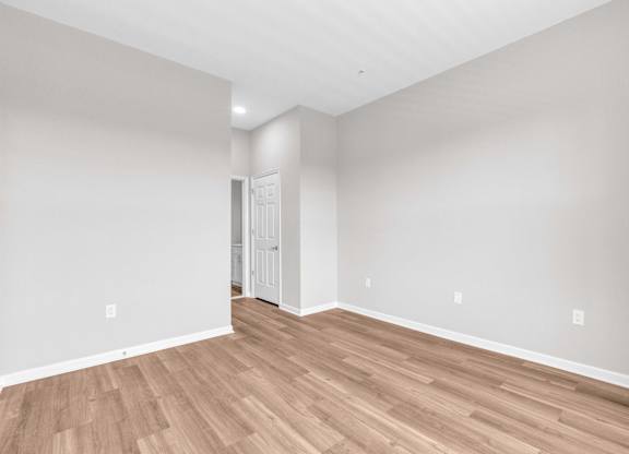 A room with wooden flooring and a white door.