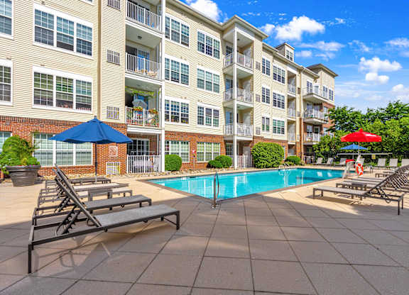 A large apartment complex with a pool and sun loungers.