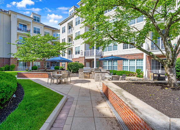 A sunny day at a residential complex with a well-maintained garden and seating area.