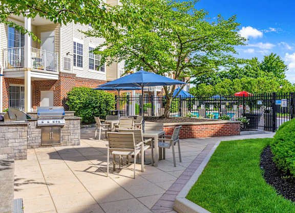 A patio with a table and chairs is surrounded by a black fence.