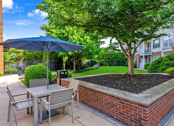 A patio with a table, chairs, and a blue umbrella.