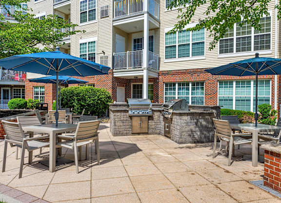 A patio with chairs and umbrellas in front of a brick building.