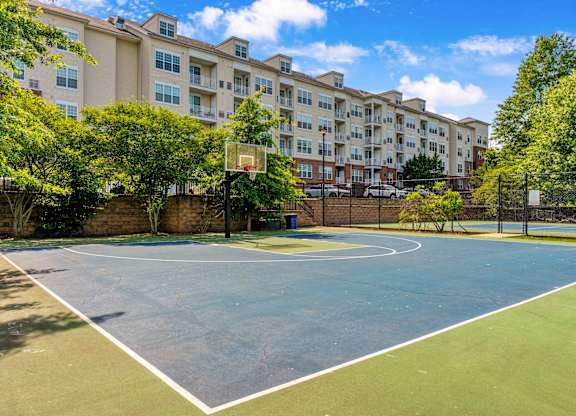 A basketball court is located in front of apartment buildings.