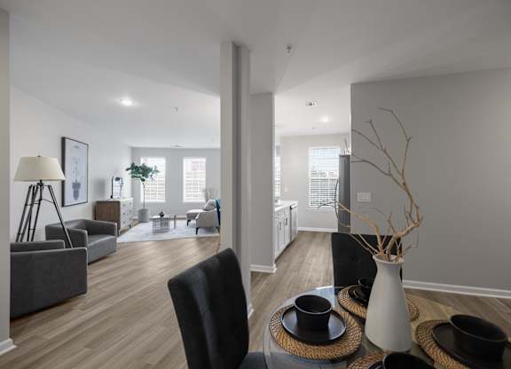 A modern living room with a black chair and a white vase on a woven tray.