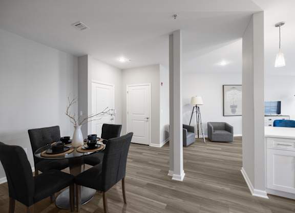 A dining room with a table set for two and a kitchen area in the background.