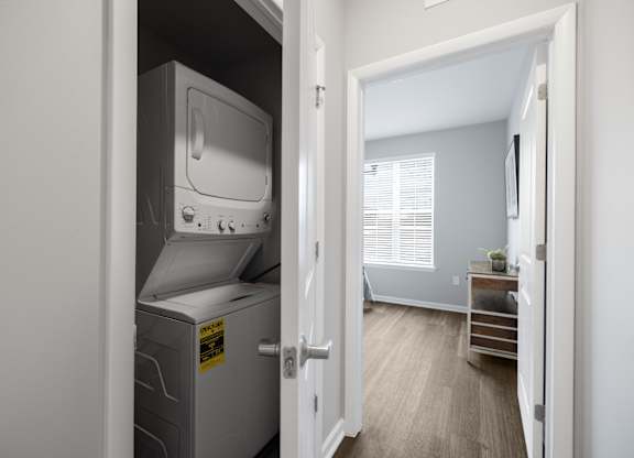 A small room with a white fridge and a door open to a hallway.