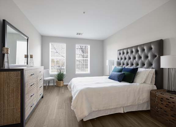 A bedroom with a large bed, a wooden dresser, and a mirror.
