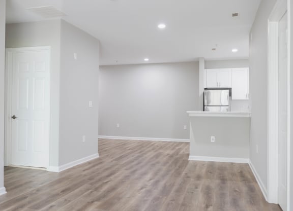 an empty living room and kitchen with white walls and wood flooring at The Lena, Raritan, NJ 08869