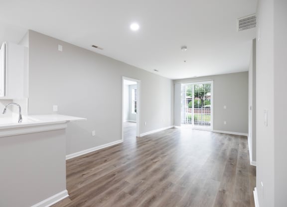 a renovated living room and kitchen with white walls and wood flooring at The Lena, Raritan, NJ 08869