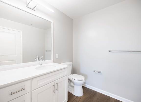 A white bathroom with a toilet, sink, and mirror.