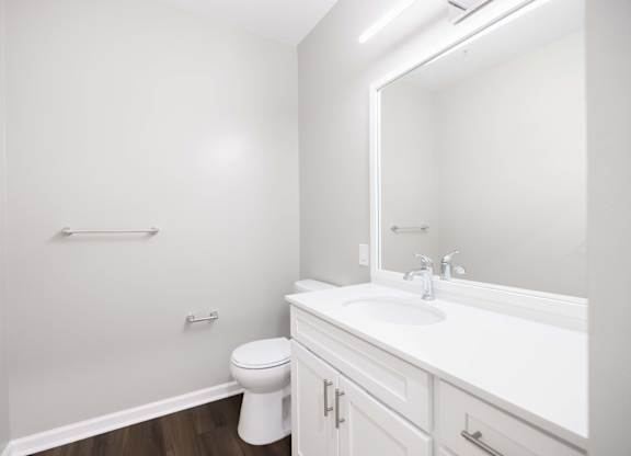 A white bathroom with a toilet, sink, and mirror.