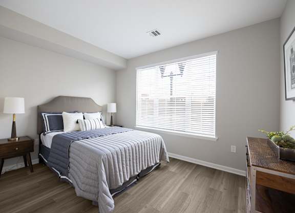 A bedroom with a bed, nightstand, and window at Harbor Pointe Apartments, New Jersey, 07002