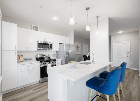 A modern kitchen with a white countertop and blue chairs at Harbor Pointe Apartments, Bayonne, New Jersey