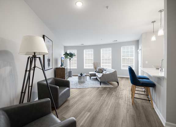 A well-lit living room with a grey sofa, a black chair, and a wooden floor at Harbor Pointe Apartments, Bayonne