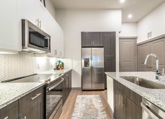 A kitchen with a refrigerator, microwave, and sink.at The Bridge at McKinney, McKinney