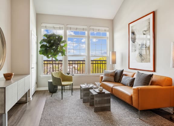 a living room with a brown couch and a large plant in front of a window at Metro 303, New York, 11550