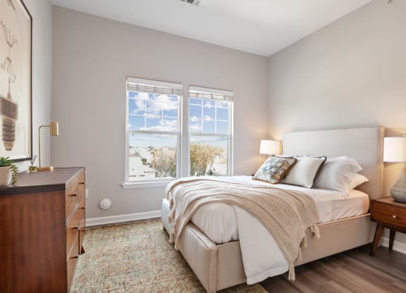 a bedroom with a bed and two windows at Metro 303, Hempstead, NY