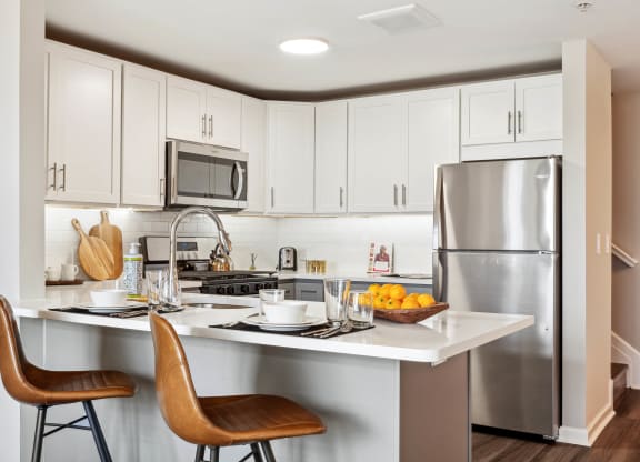 a kitchen with white cabinets and stainless steel appliances at Metro 303, Hempstead, NY