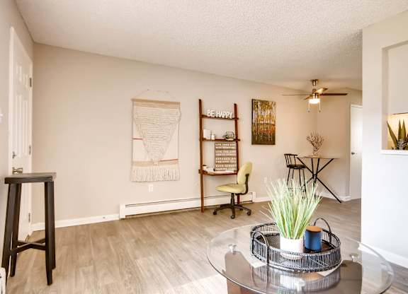 A living room with a glass coffee table and a yellow chair at Mountain Vista Apartments, Lakewood