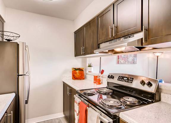 A kitchen with a stove top oven and a refrigerator at Mountain Vista Apartments, Lakewood, CO, 80228