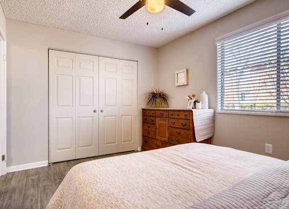 A bedroom with a bed, dresser, and a ceiling fan at Mountain Vista Apartments, Lakewood, Colorado