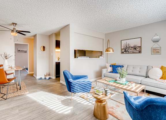 A living room with a white couch, blue armchair, and a coffee table at Mountain Vista Apartments, Colorado