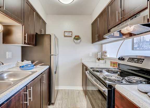 A kitchen with a stove top oven and a refrigerator at Mountain Vista Apartments, Lakewood