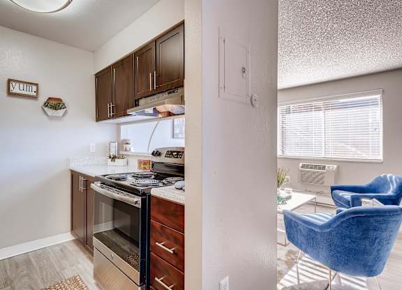 A kitchen with a refrigerator, oven, and a blue chair at Mountain Vista Apartments, Lakewood, CO
