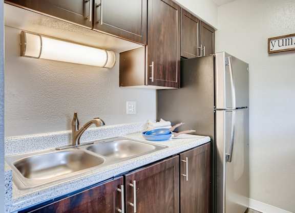 A kitchen with a sink, refrigerator, and cabinets at Mountain Vista Apartments, Colorado, 80228