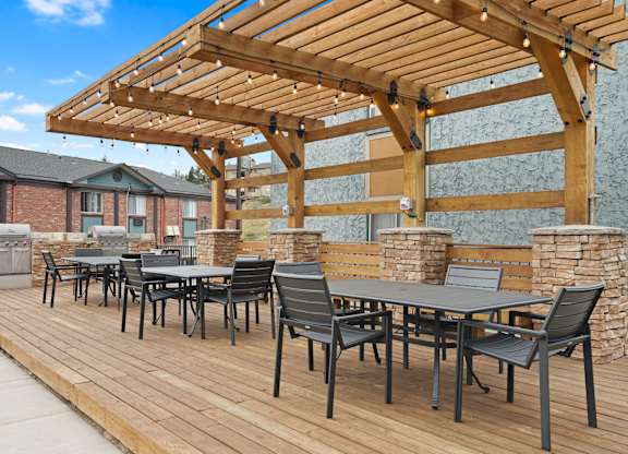 A wooden deck with a table and chairs under a pergola at Mountain Vista Apartments, Lakewood, CO, 80228