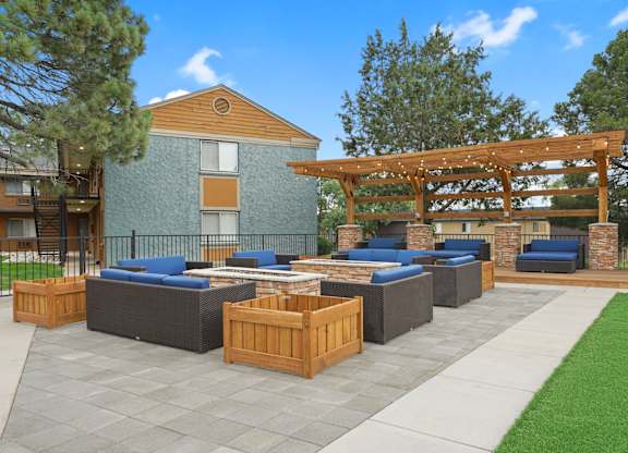 A patio with a wooden pergola and grey cushioned seating at Mountain Vista Apartments, Colorado