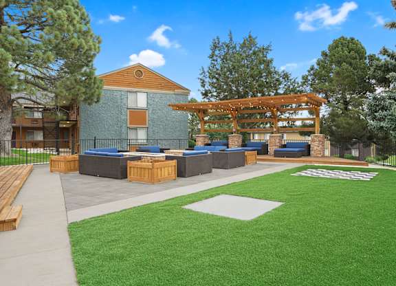 A large building with a wooden pergola and a green lawn in front at Mountain Vista Apartments, Lakewood, Colorado