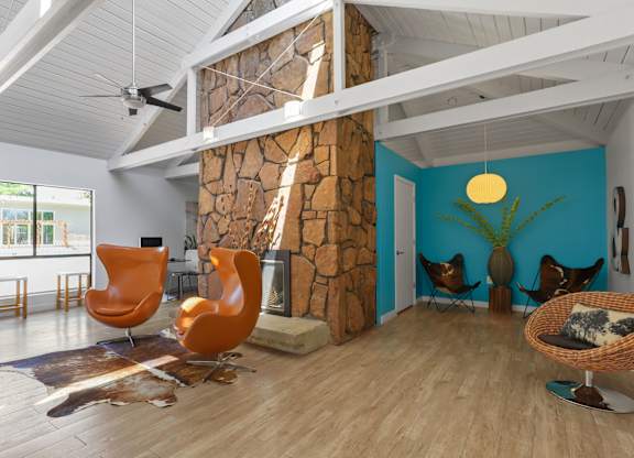 A room with a stone fireplace and wooden floors at The Ranch at Bear Creek Apartments, Lakewood, Colorado